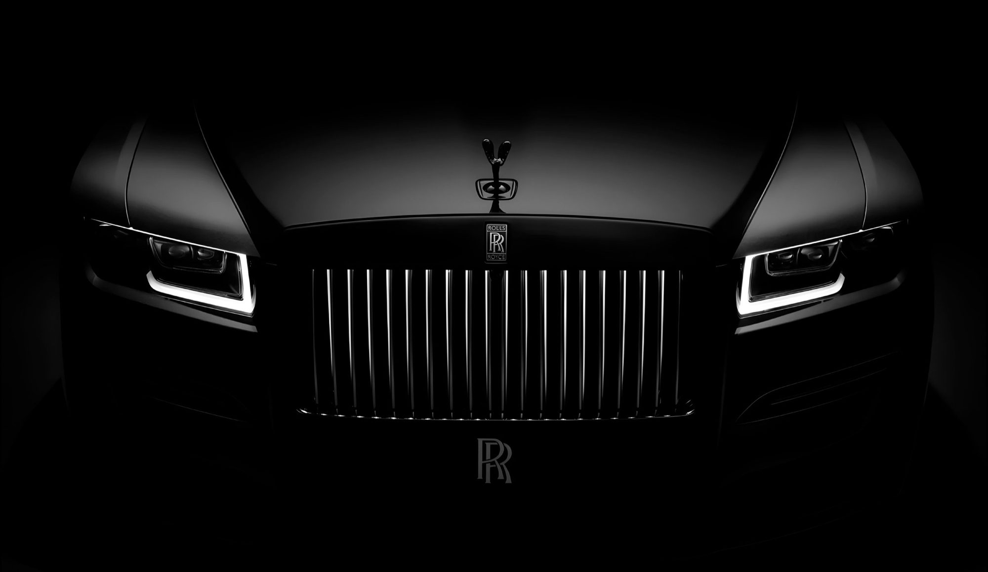 The Rolls-Royce Black Badge, head-on, grille lit against the dark